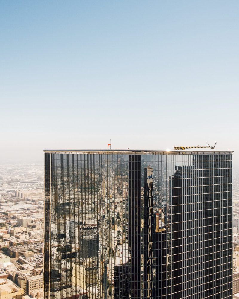 A gleaming skyscraper rises above the sprawling urban landscape under a clear blue sky.